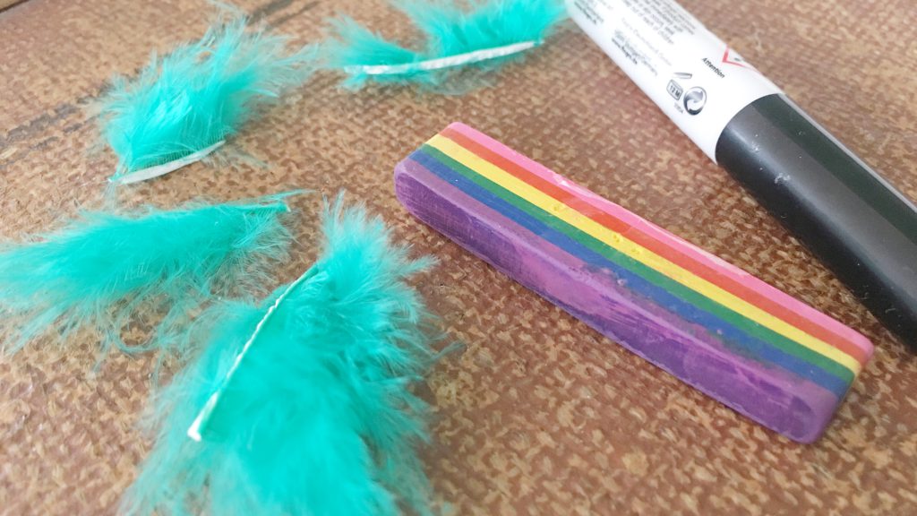Kinderschminken mit einem Regenbogenstift und Federn
