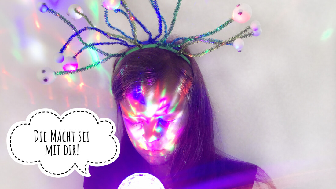 Ein Alienkopfschmuck auf Pfeifenputzern gibt dem Weltraumparty Outfit den letzten Schliff