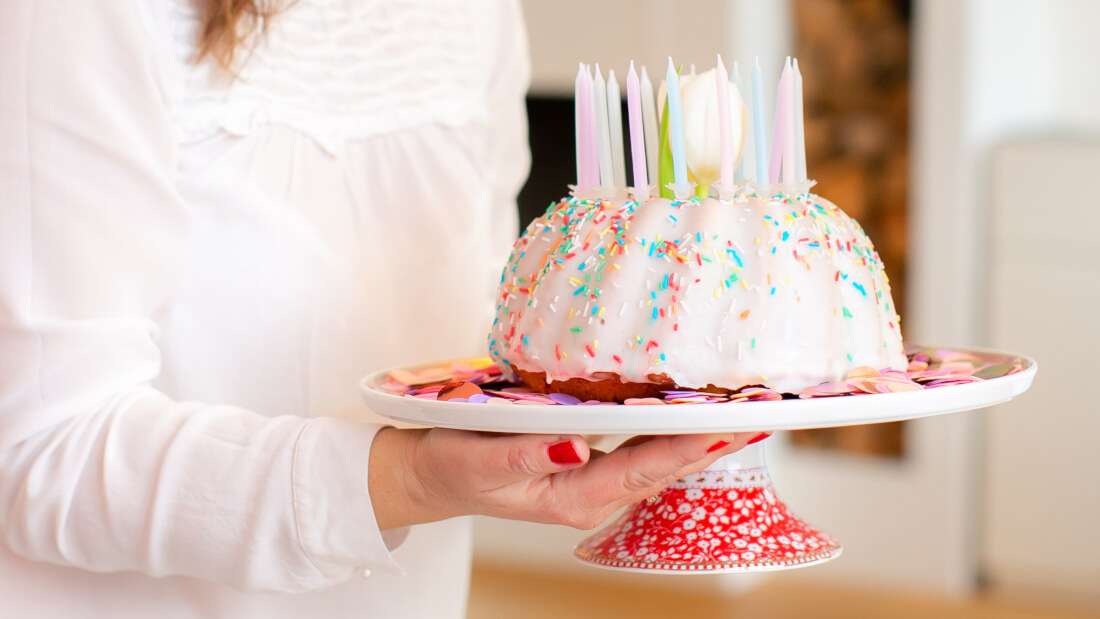 Ein einfacher Rührkuchen mit weißer Glasur und bunten Streuseln und Kerzen in Pastellfarben ist perfekt für eure Feen- und Einhornparty